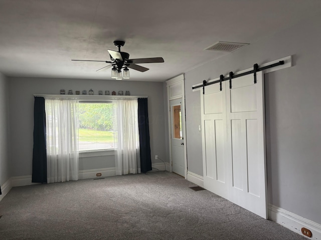 324 E Main St, Cardington, OH 43315 - unfurnished bedroom featuring a barn door, carpet flooring, and a ceiling fan