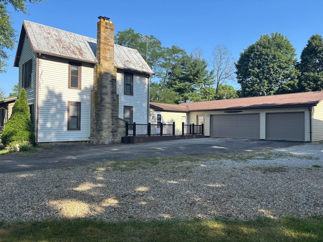 324 E Main St, Cardington, OH 43315 - rear view of property featuring a chimney, gravel driveway, a standing seam roof, a metal roof, and a garage