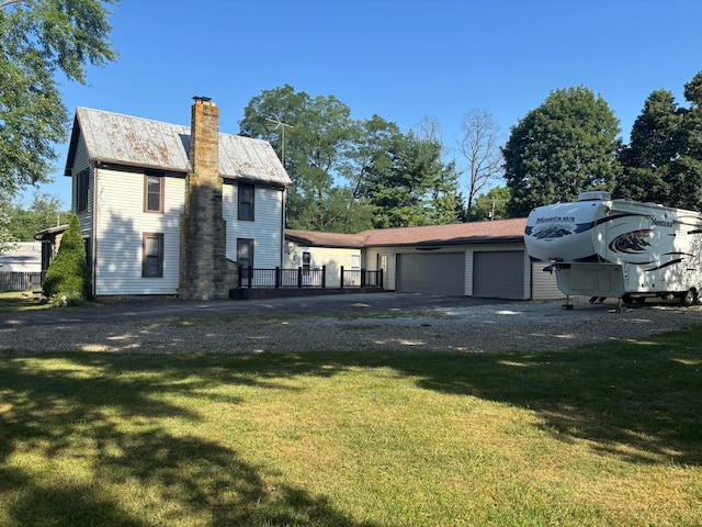 324 E Main St, Cardington, OH 43315 - back of property featuring a chimney, gravel driveway, an attached garage, a yard, and a metal roof