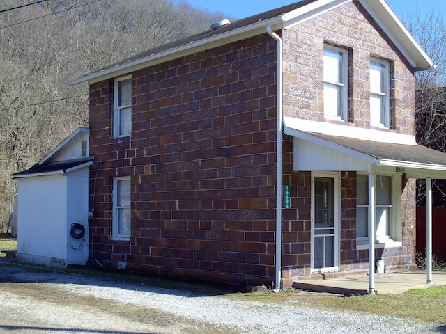 view of property exterior with brick siding and a porch