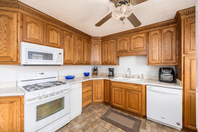 kitchen featuring light countertops, white appliances, a sink, and brown cabinets