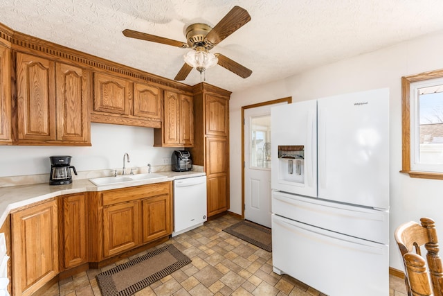 kitchen with brown cabinets, white appliances, light countertops, and a sink