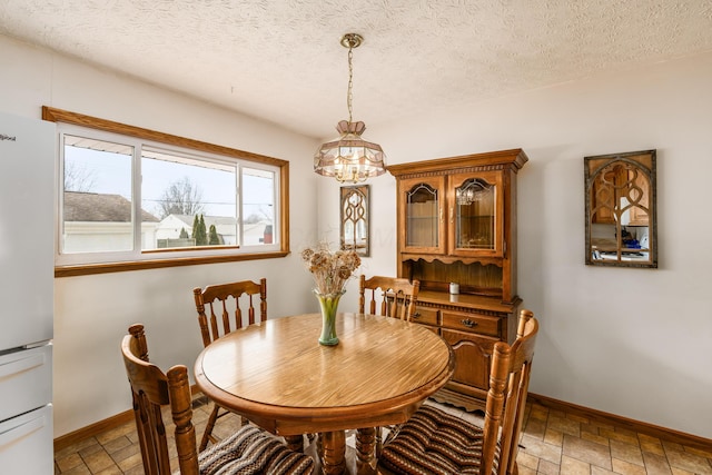 dining space with a textured ceiling, stone finish floor, and baseboards