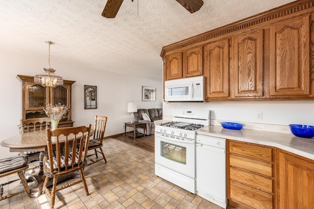 kitchen featuring ceiling fan with notable chandelier, white appliances, light countertops, brown cabinetry, and decorative light fixtures