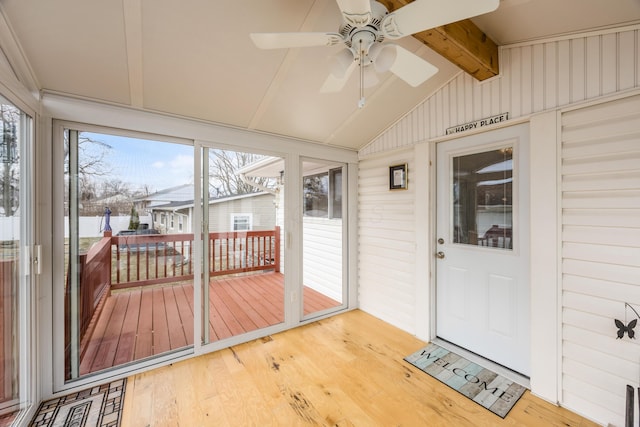 unfurnished sunroom featuring a ceiling fan and vaulted ceiling with beams