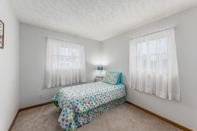 bedroom featuring baseboards, a textured ceiling, and carpet flooring