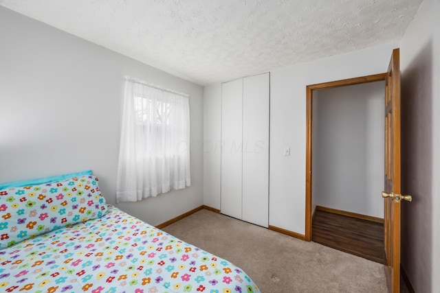 unfurnished bedroom with carpet, a closet, baseboards, and a textured ceiling