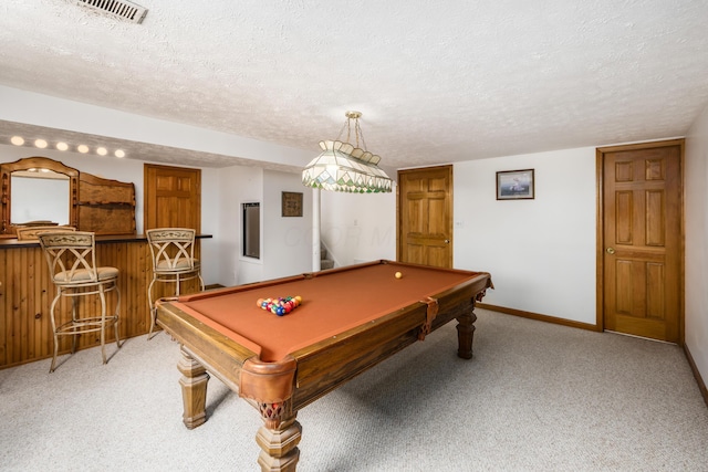 game room with a textured ceiling, a bar, visible vents, and light colored carpet