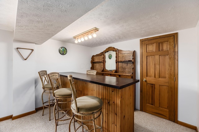 bar featuring baseboards, carpet flooring, a textured ceiling, and a dry bar