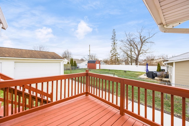 wooden deck with a fenced backyard, a detached garage, a lawn, and an outdoor structure