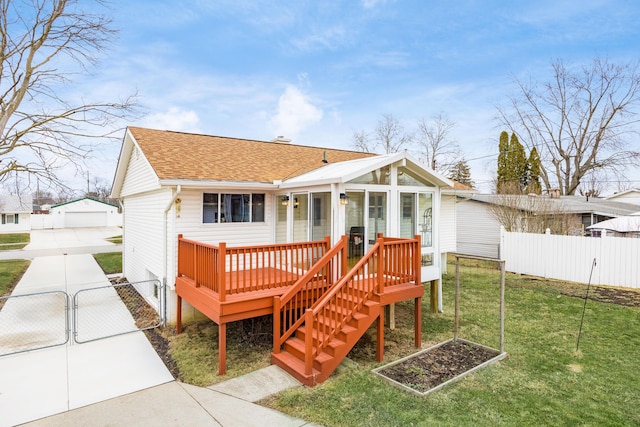 back of property with an outbuilding, a shingled roof, a lawn, a gate, and fence