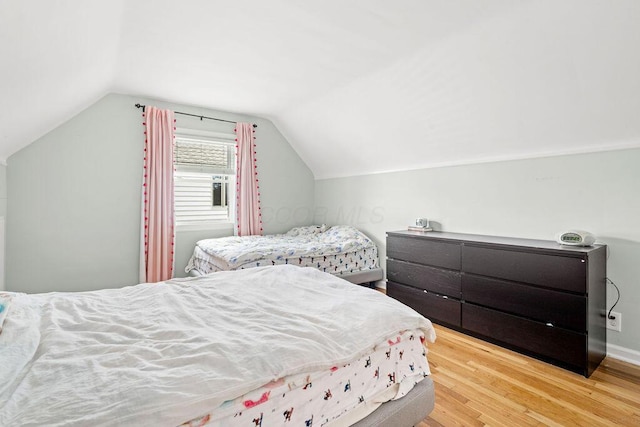 bedroom with lofted ceiling, baseboards, and wood finished floors