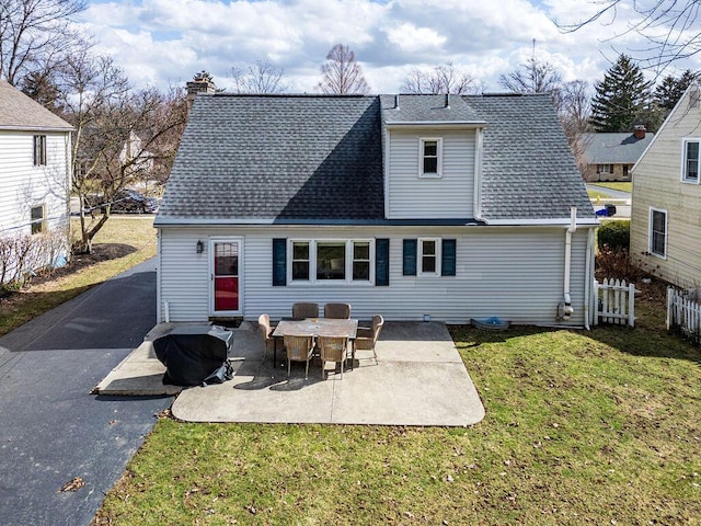 rear view of house featuring a yard, a chimney, a shingled roof, a patio area, and fence