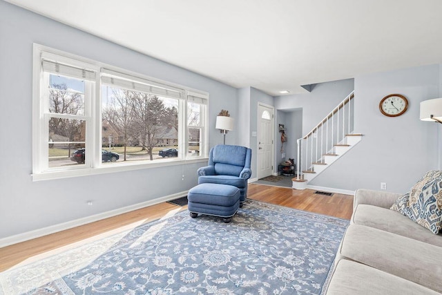 living area featuring stairway, wood finished floors, visible vents, and baseboards