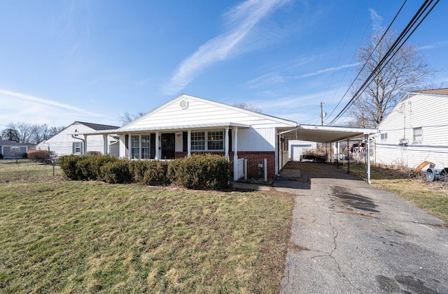 view of front of house with an attached carport, brick siding, fence, driveway, and a front lawn