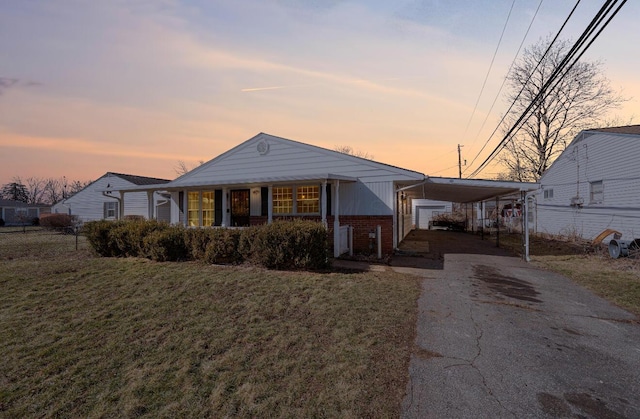 view of front of property featuring brick siding, a front yard, fence, a carport, and driveway