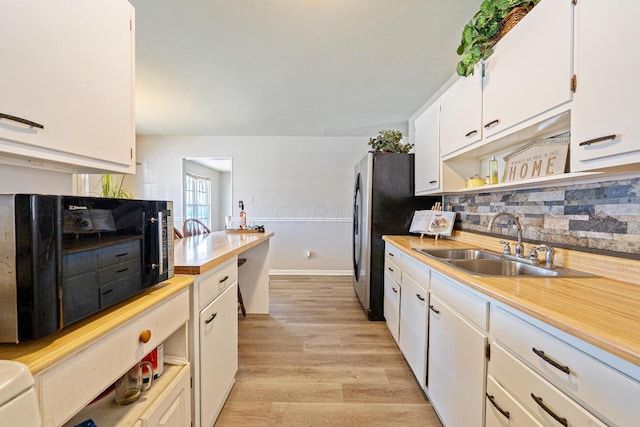 kitchen with light wood finished floors, open shelves, light countertops, white cabinets, and a sink