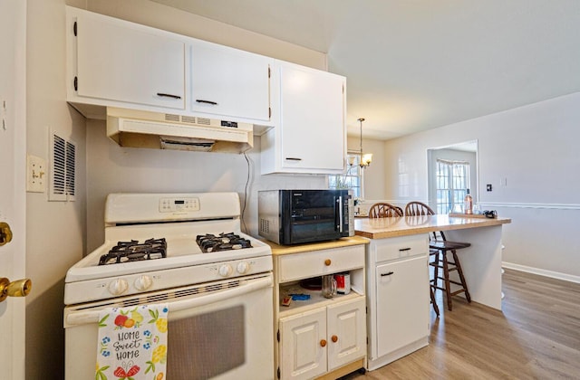 kitchen featuring under cabinet range hood, light wood-style flooring, white gas range, and white cabinetry