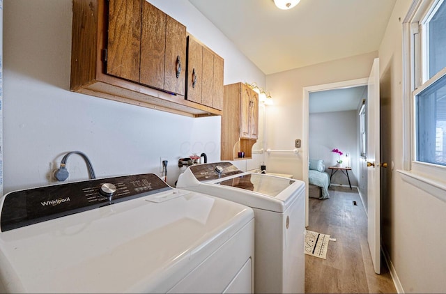 laundry room with light wood-type flooring, cabinet space, baseboards, and washer and clothes dryer