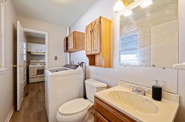 bathroom with independent washer and dryer, vanity, toilet, and wood finished floors