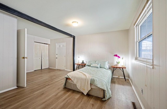 bedroom with visible vents, baseboards, and wood finished floors