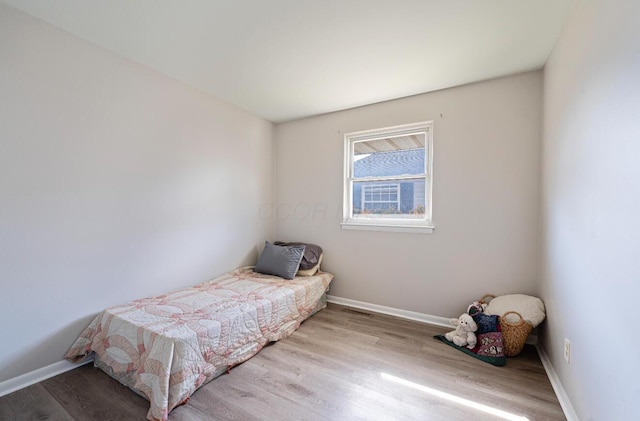 bedroom featuring visible vents, baseboards, and wood finished floors