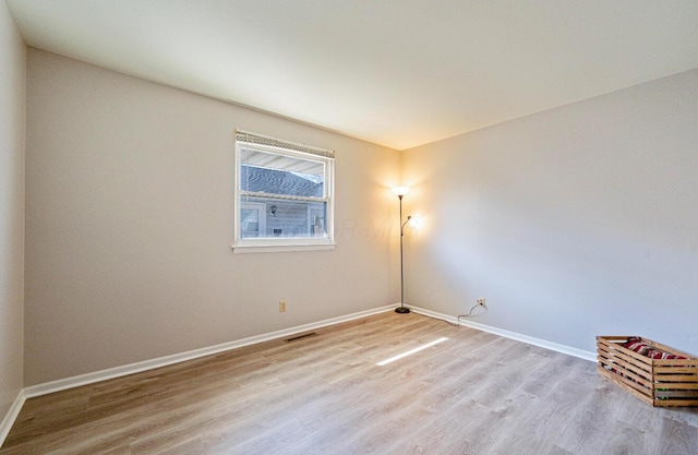 empty room featuring baseboards, visible vents, and wood finished floors