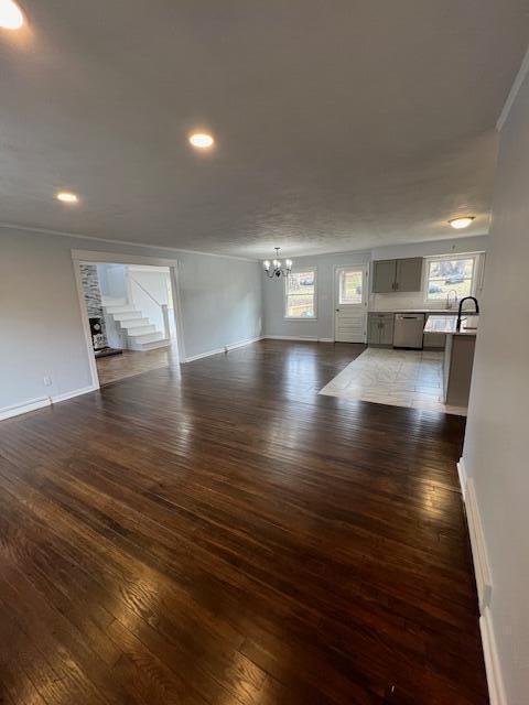 unfurnished living room with baseboards, dark wood-style flooring, recessed lighting, and an inviting chandelier