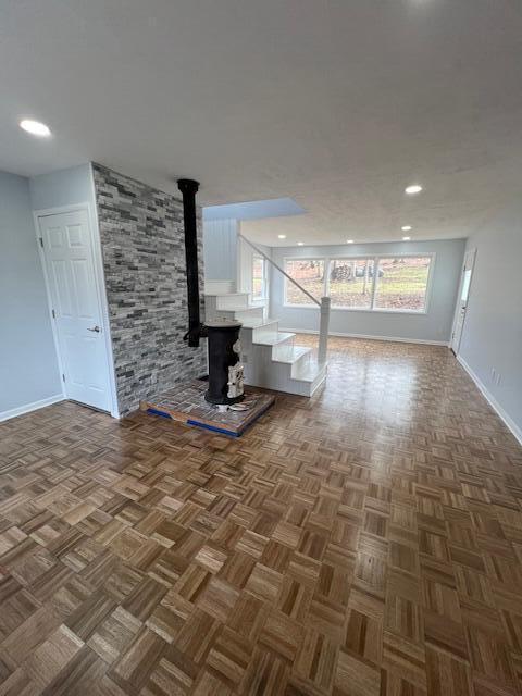 unfurnished living room with recessed lighting, a wood stove, and baseboards