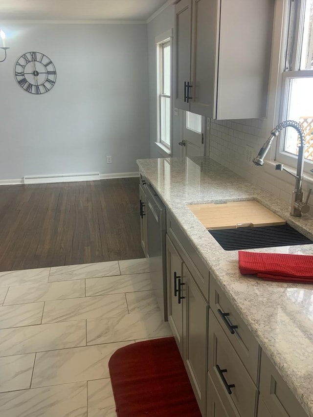 kitchen with a wealth of natural light, ornamental molding, a sink, marble finish floor, and stainless steel dishwasher