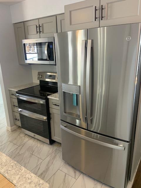 kitchen featuring marble finish floor, gray cabinets, and stainless steel appliances