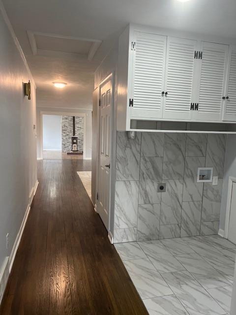 corridor with attic access, marble finish floor, and baseboards