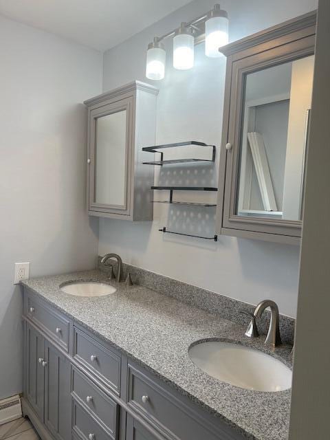 bathroom with double vanity, a baseboard heating unit, and a sink