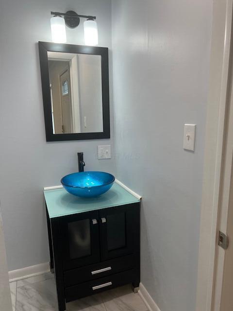 bathroom featuring marble finish floor, baseboards, and vanity