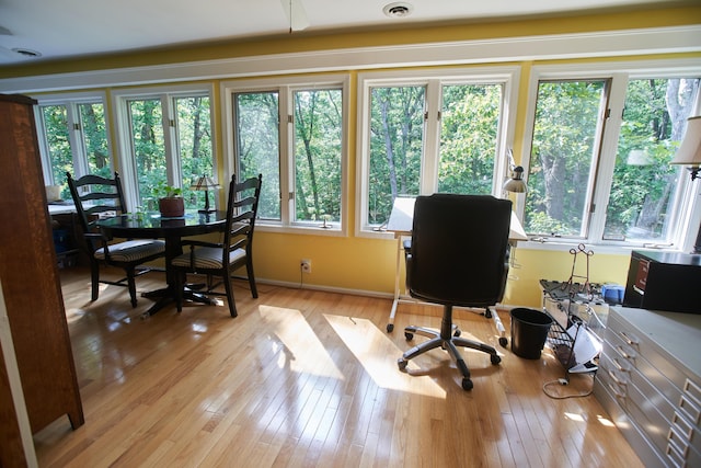 office space with baseboards, light wood-style floors, and a healthy amount of sunlight