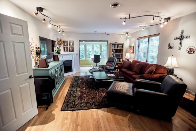 living room with rail lighting, visible vents, a fireplace, and light wood-style flooring