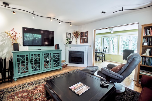 living room featuring baseboards, visible vents, wood finished floors, a fireplace, and track lighting