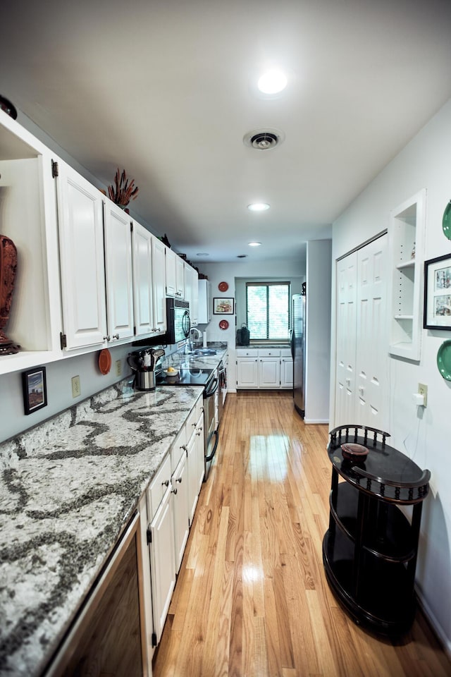 kitchen featuring visible vents, white cabinets, appliances with stainless steel finishes, light stone countertops, and light wood-type flooring