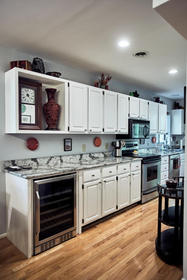 kitchen featuring beverage cooler, appliances with stainless steel finishes, visible vents, and light wood-style floors