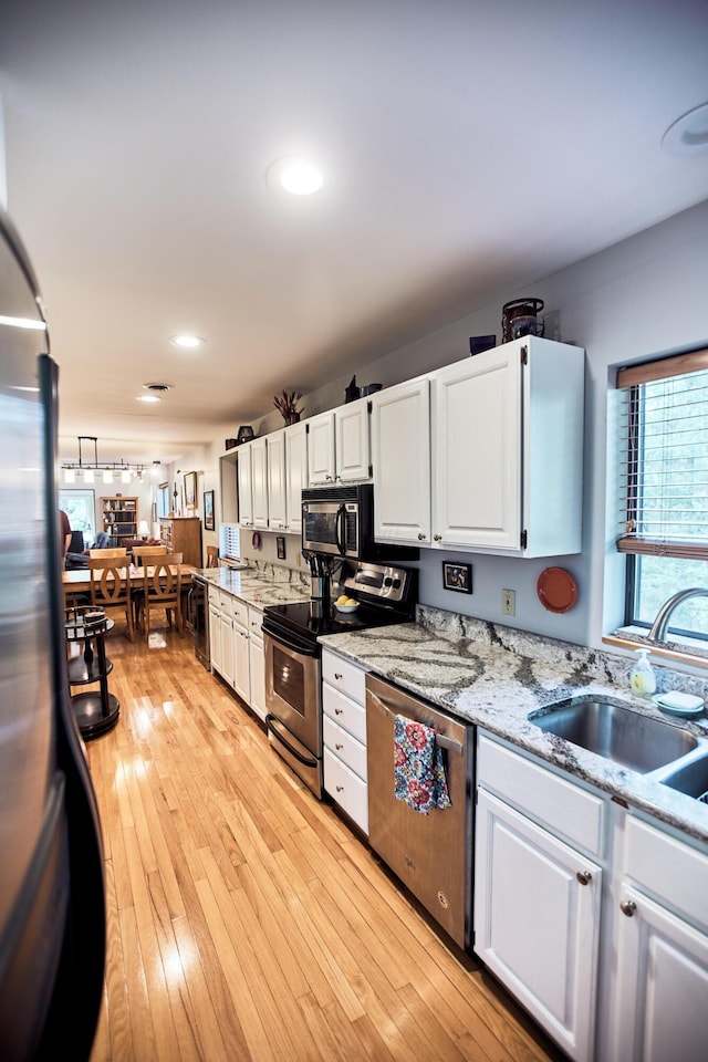 kitchen featuring light wood-type flooring, white cabinetry, stainless steel appliances, and a sink