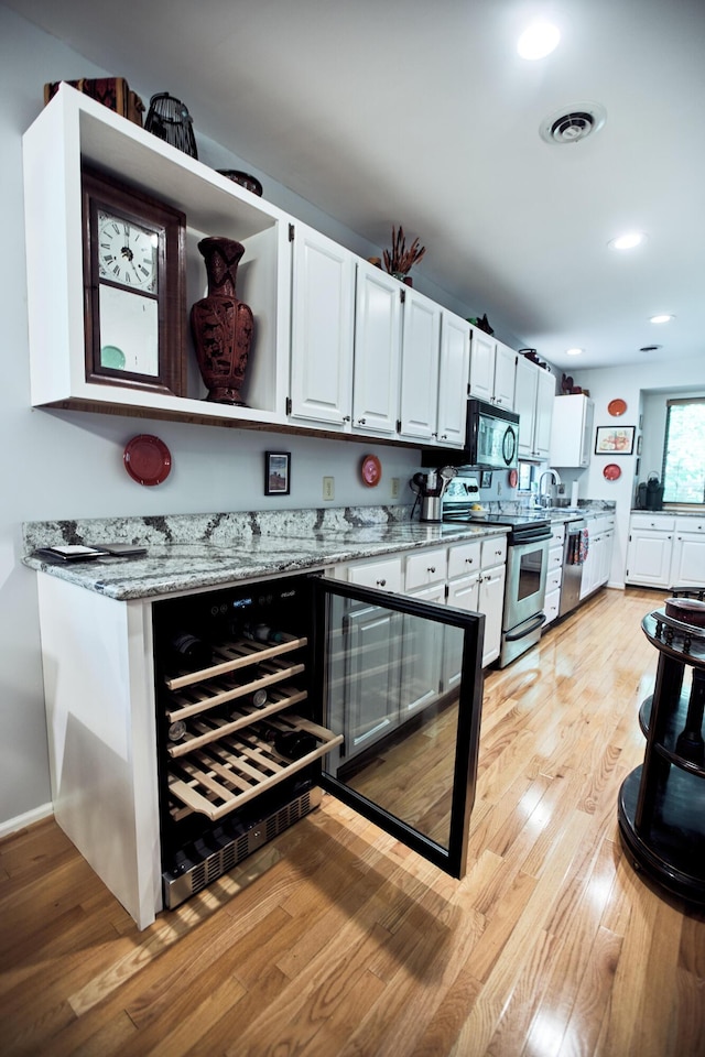 kitchen featuring visible vents, white cabinets, appliances with stainless steel finishes, light wood-type flooring, and light stone countertops