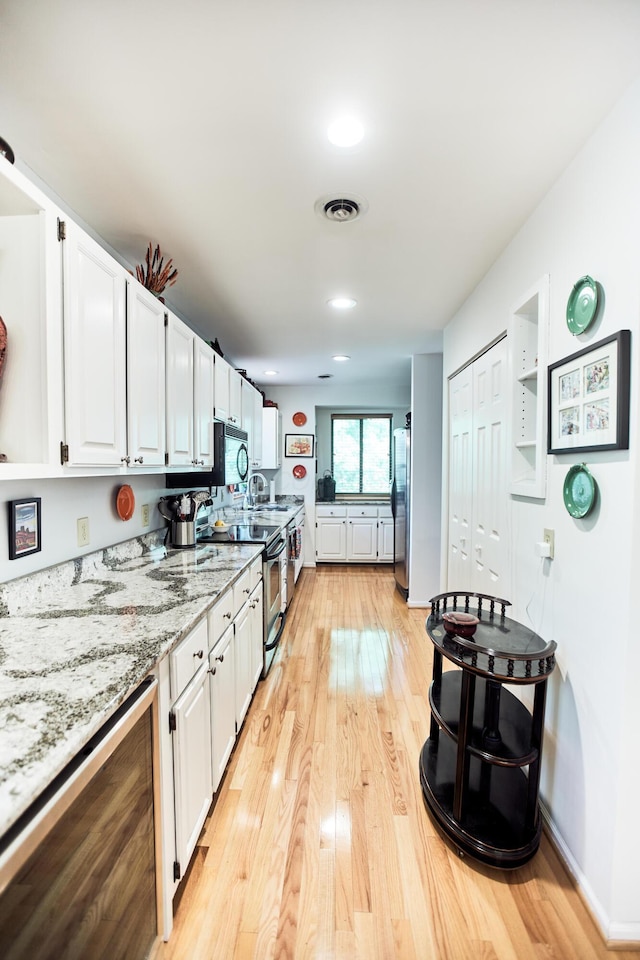 kitchen featuring stainless steel appliances, visible vents, light wood finished floors, and white cabinetry