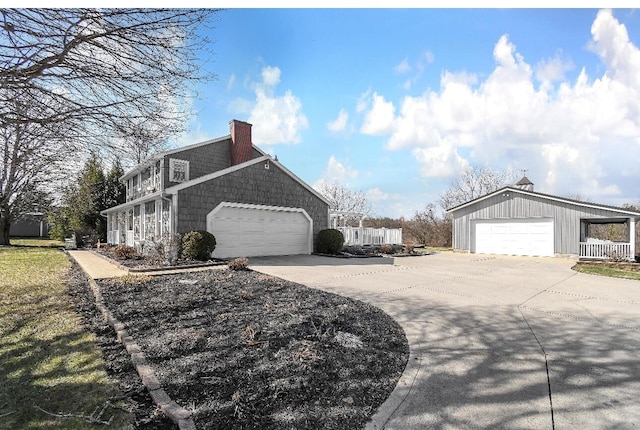 view of side of home featuring driveway, a chimney, and an attached garage