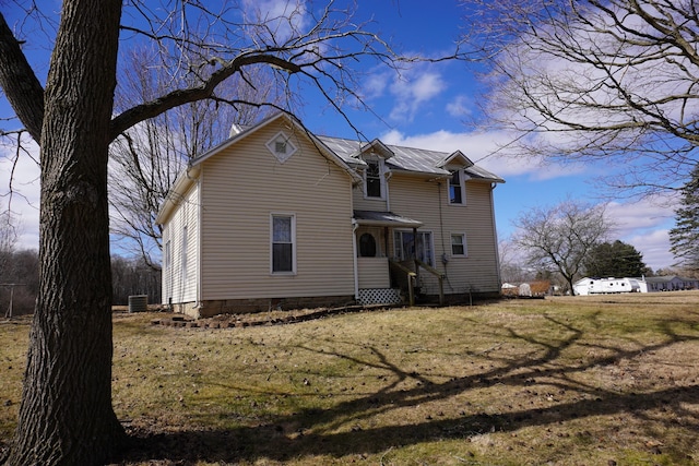 rear view of property with central AC unit and a yard