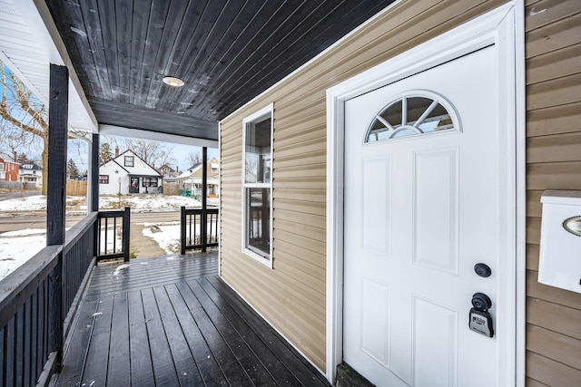 snow covered deck featuring covered porch and a residential view