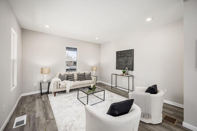 living room featuring visible vents, baseboards, and wood finished floors