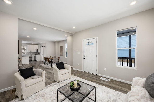 living room with recessed lighting, visible vents, baseboards, and wood finished floors