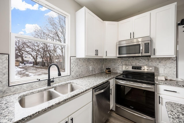 kitchen with white cabinets, backsplash, stainless steel appliances, and a sink