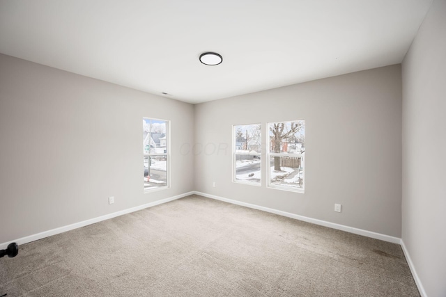 carpeted empty room with a healthy amount of sunlight and baseboards