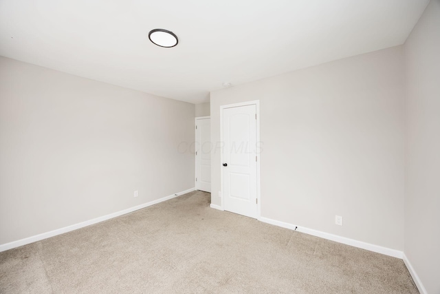 unfurnished room featuring light colored carpet and baseboards